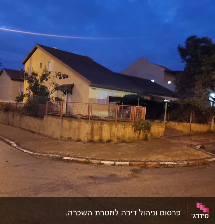 בית פרטי עם גדר ברחוב בשעת ערב